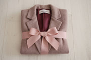 Kristina Collins jacket folded on a table with a bow